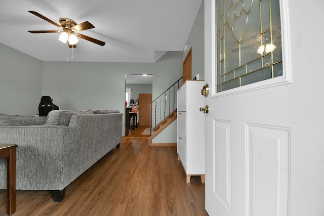 living room featuring ceiling fan, dark hardwood / wood-style floors, and a textured ceiling