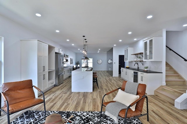 kitchen featuring sink, decorative light fixtures, a center island, stainless steel refrigerator, and white cabinets