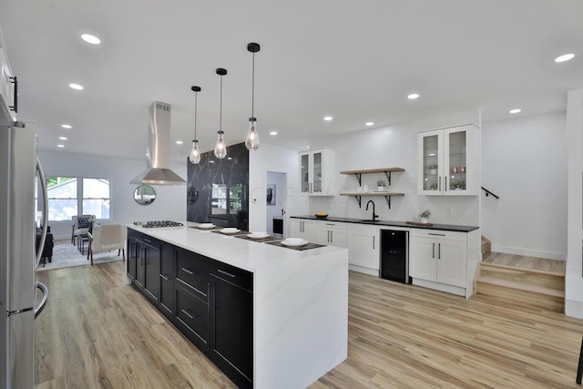 kitchen with wine cooler, island range hood, stainless steel refrigerator, a kitchen island, and white cabinets