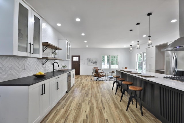 kitchen featuring stainless steel appliances, white cabinetry, light hardwood / wood-style flooring, and decorative light fixtures