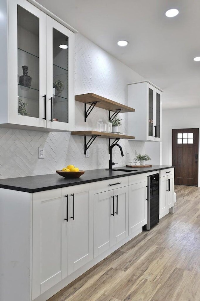 kitchen with white cabinetry, sink, beverage cooler, and light hardwood / wood-style floors