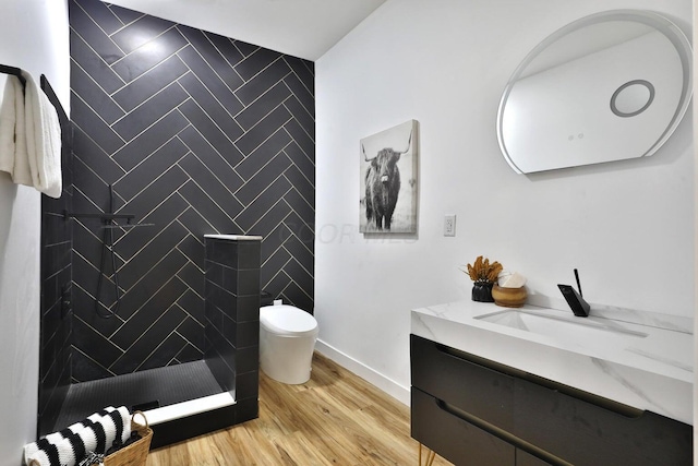 bathroom with vanity, hardwood / wood-style floors, toilet, and a tile shower