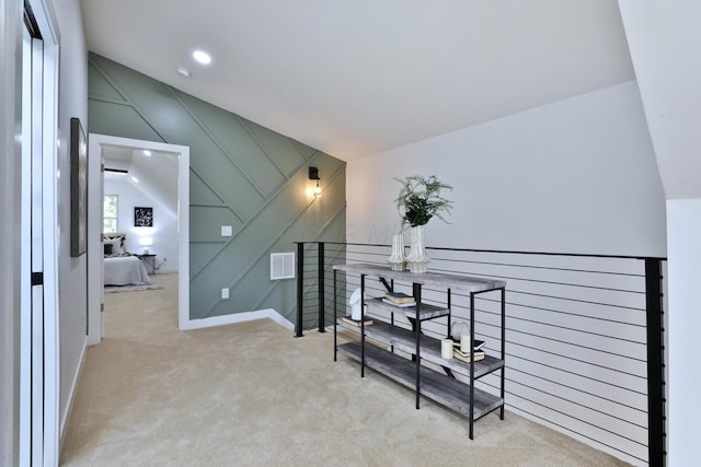 hallway with vaulted ceiling and light carpet