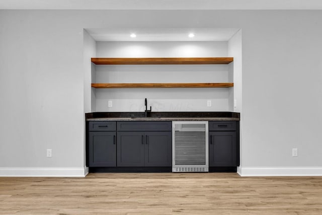 bar with sink, gray cabinetry, beverage cooler, and light hardwood / wood-style flooring