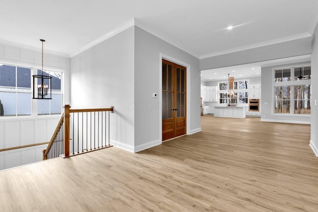 unfurnished living room featuring an inviting chandelier, sink, light hardwood / wood-style flooring, and ornamental molding