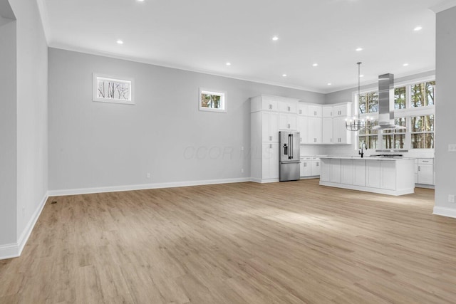 unfurnished living room featuring sink, crown molding, light hardwood / wood-style flooring, and a chandelier