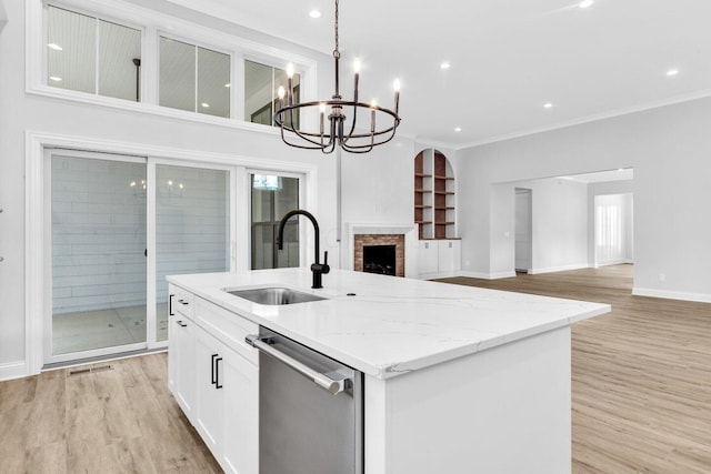 kitchen featuring sink, a kitchen island with sink, stainless steel dishwasher, light stone countertops, and light hardwood / wood-style flooring