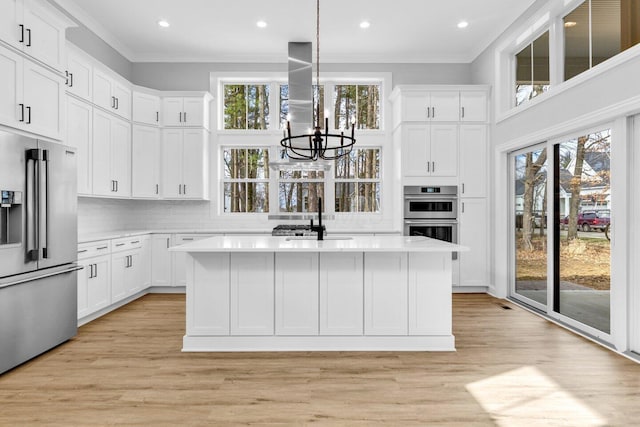 kitchen featuring stainless steel appliances, island exhaust hood, sink, and a kitchen island with sink