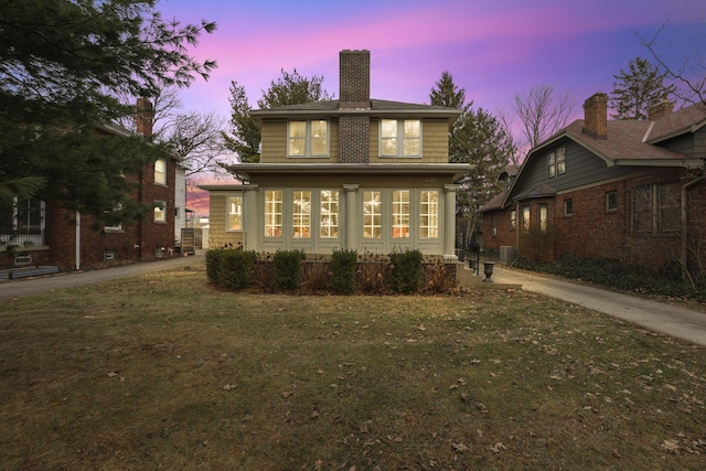 back house at dusk featuring cooling unit and a lawn