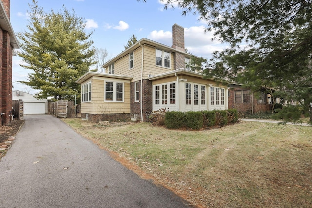 exterior space featuring a garage, an outdoor structure, and a lawn