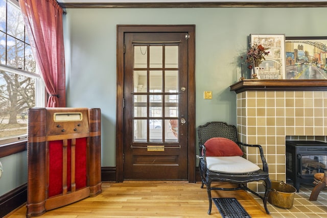 doorway with a healthy amount of sunlight, a tile fireplace, and light wood-type flooring