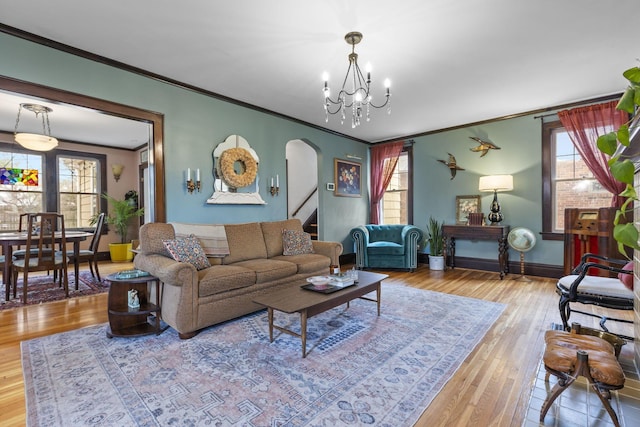 living room featuring an inviting chandelier, ornamental molding, hardwood / wood-style floors, and a wealth of natural light