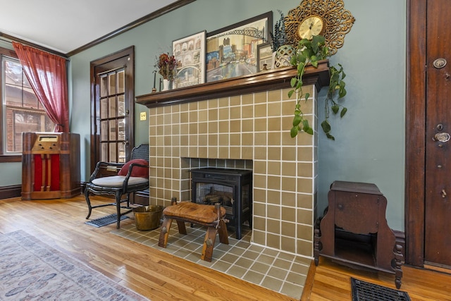 sitting room featuring a tile fireplace, crown molding, and wood-type flooring