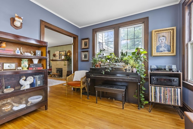 misc room featuring a tile fireplace, ornamental molding, and light hardwood / wood-style flooring