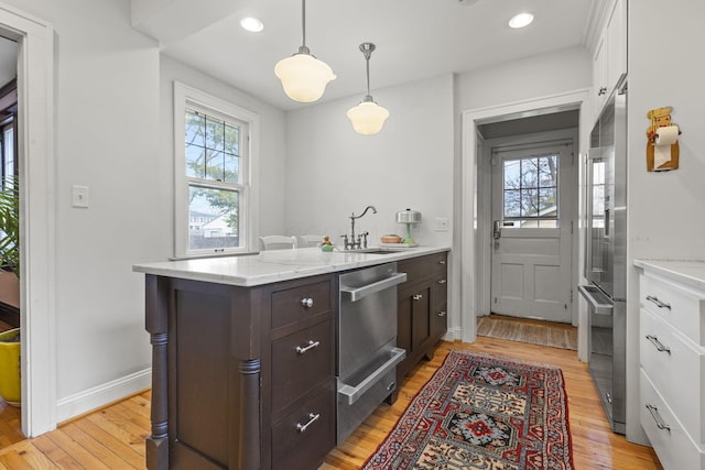 kitchen with dark brown cabinetry, sink, decorative light fixtures, light wood-type flooring, and white cabinets