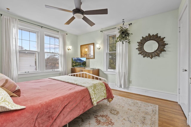 bedroom with multiple windows, ceiling fan, and light wood-type flooring