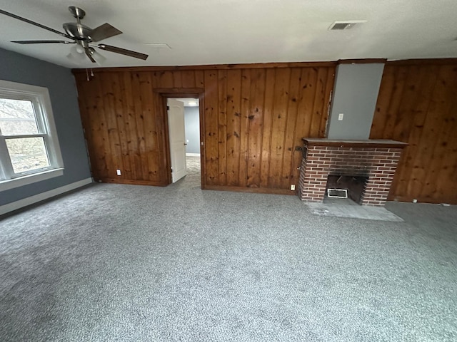 unfurnished living room featuring a fireplace, wooden walls, and ceiling fan