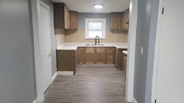 kitchen with sink, decorative backsplash, and light hardwood / wood-style flooring