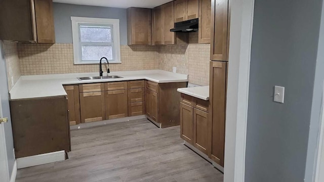 kitchen with tasteful backsplash, sink, and light hardwood / wood-style floors