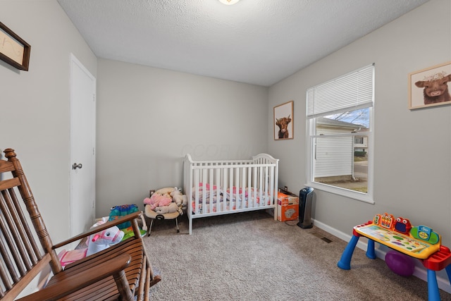 carpeted bedroom featuring a textured ceiling and a crib