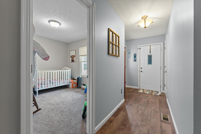 interior space with dark hardwood / wood-style floors, a textured ceiling, and a crib