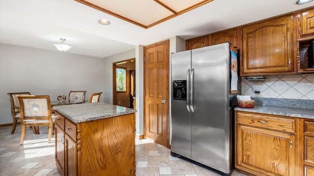 kitchen featuring stainless steel refrigerator with ice dispenser, a center island, light stone counters, and tasteful backsplash