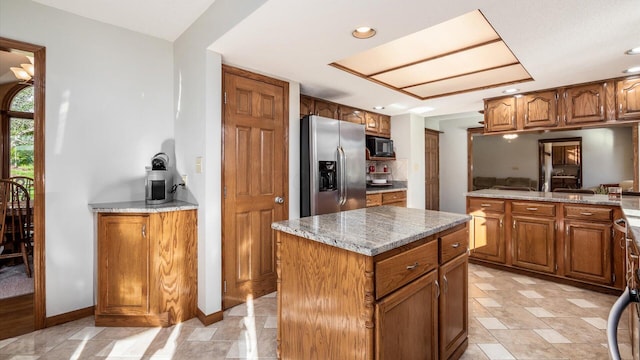 kitchen featuring black microwave, light stone countertops, a center island, and stainless steel refrigerator with ice dispenser