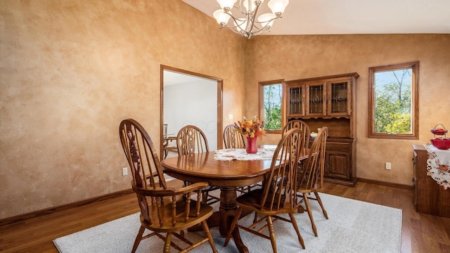 dining area with lofted ceiling, dark wood-type flooring, and a notable chandelier