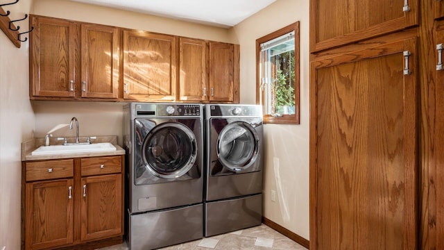 clothes washing area with cabinets, washing machine and dryer, and sink