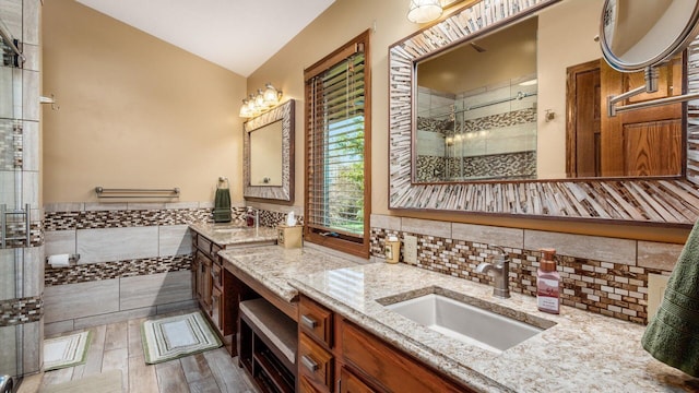 bathroom featuring vaulted ceiling, tile walls, hardwood / wood-style flooring, vanity, and a shower with door