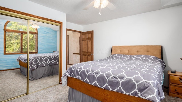 bedroom featuring ceiling fan, light colored carpet, a textured ceiling, and a closet