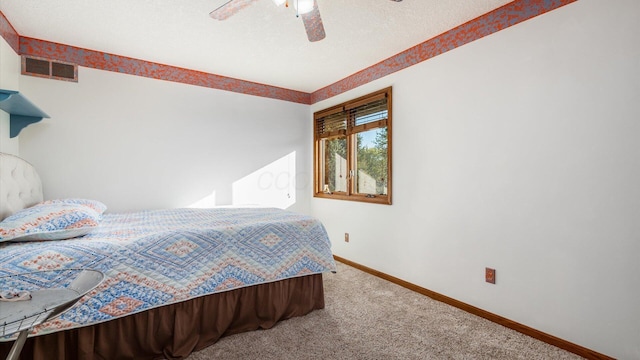 carpeted bedroom featuring ceiling fan and a textured ceiling