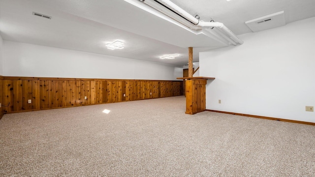 carpeted spare room featuring wooden walls