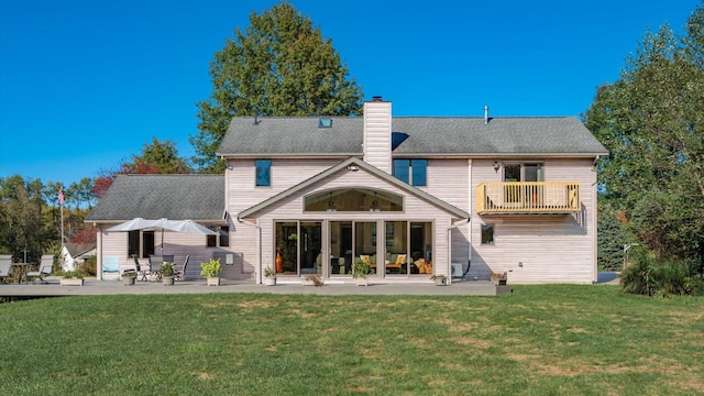 rear view of house with a yard, a patio, and a balcony