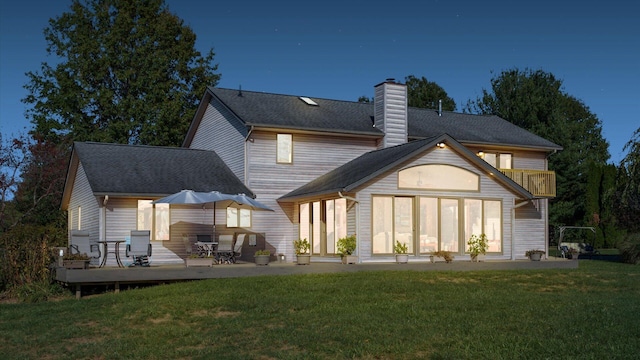 rear view of property featuring a yard and a deck