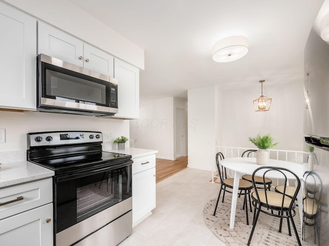 kitchen with pendant lighting, light stone countertops, stainless steel appliances, and white cabinets