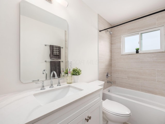 full bathroom featuring vanity, tiled shower / bath, and toilet