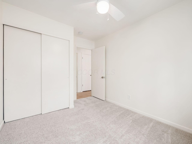 unfurnished bedroom with light carpet, a closet, and ceiling fan