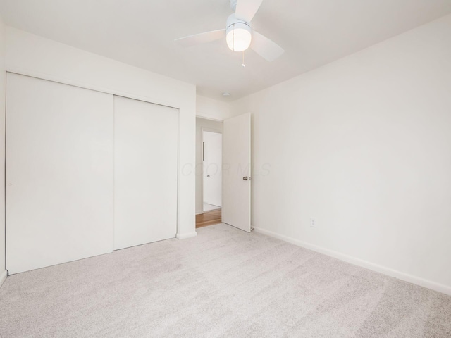 unfurnished bedroom with light carpet, ceiling fan, and a closet