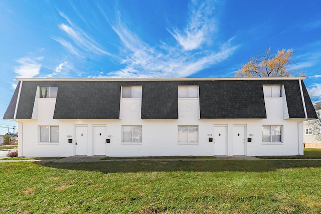 view of front of home featuring a shingled roof, a front lawn, and mansard roof