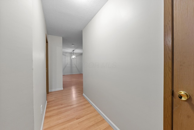 hallway with light hardwood / wood-style floors and a textured ceiling