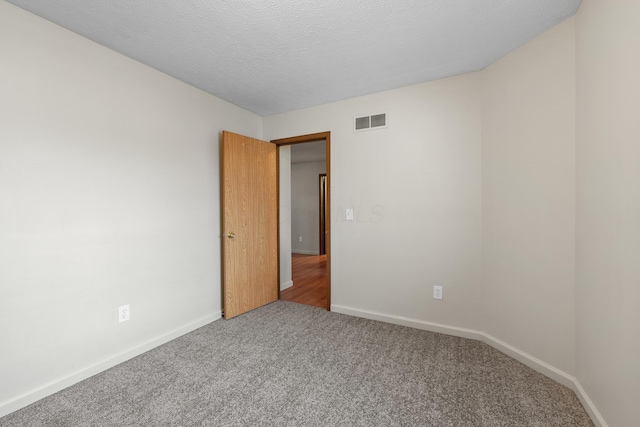 carpeted empty room featuring a textured ceiling