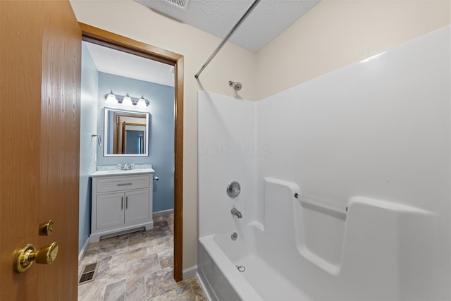 bathroom featuring vanity, shower / washtub combination, and a textured ceiling