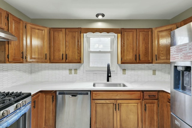 kitchen with tasteful backsplash, appliances with stainless steel finishes, sink, and exhaust hood