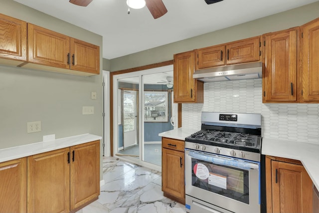 kitchen with decorative backsplash, stainless steel gas range oven, and ceiling fan