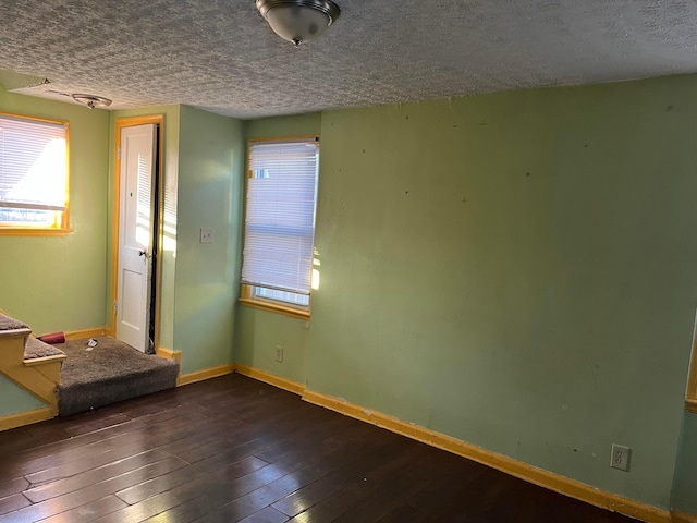 unfurnished room featuring dark wood-type flooring and a textured ceiling