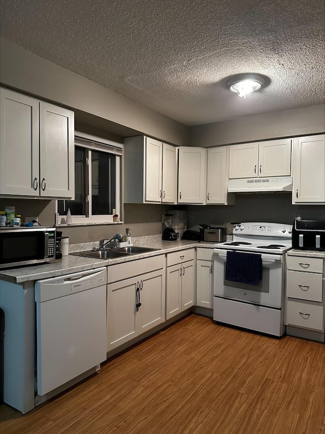 kitchen featuring white cabinetry, sink, hardwood / wood-style flooring, white appliances, and a textured ceiling