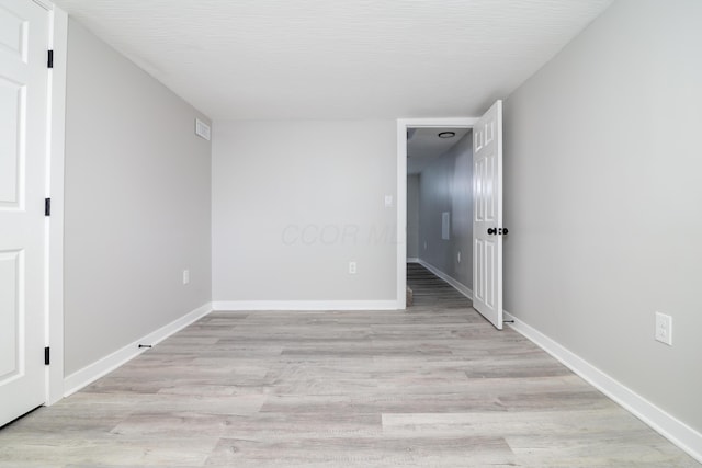 unfurnished room with a textured ceiling and light wood-type flooring