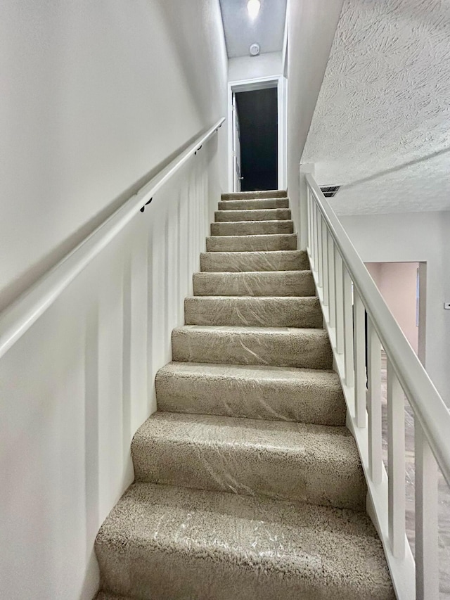 staircase with a textured ceiling