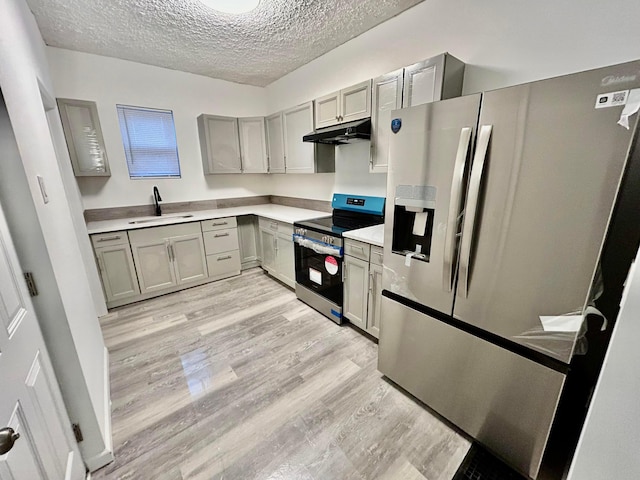 kitchen with sink, gray cabinets, appliances with stainless steel finishes, light hardwood / wood-style floors, and a textured ceiling